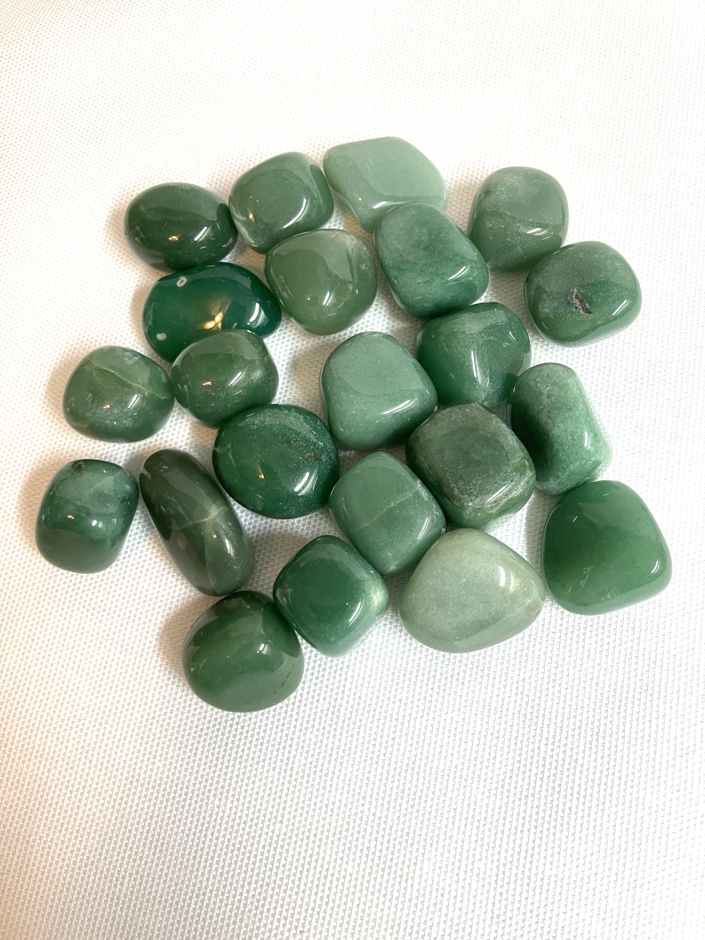 Group of Green Aventurine Tumbled Crystals on a white fabric background