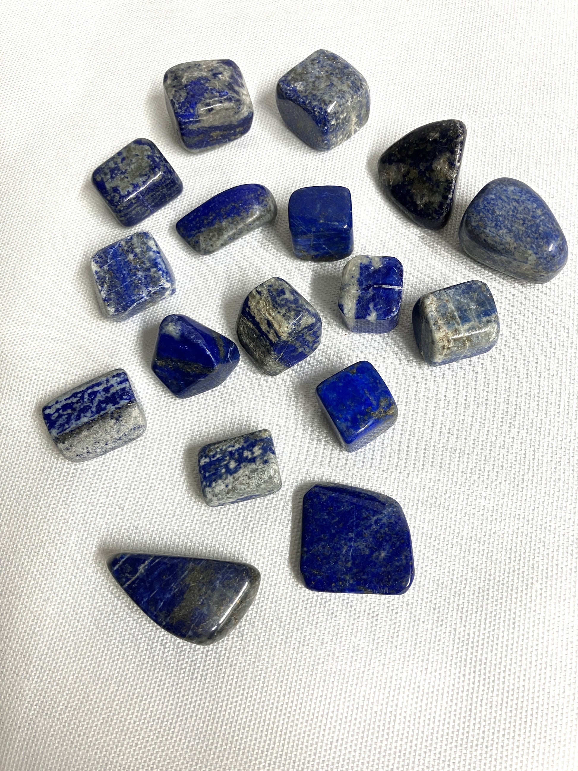 Collection of Lapis Lazuli Crystals showing the various patterns on a white fabric background