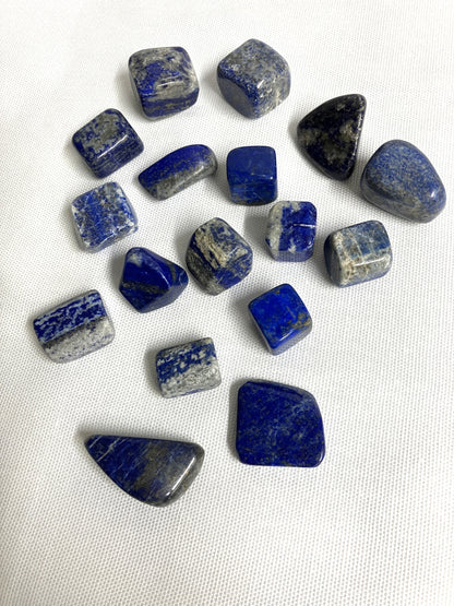 Collection of Lapis Lazuli Crystals showing the various patterns on a white fabric background