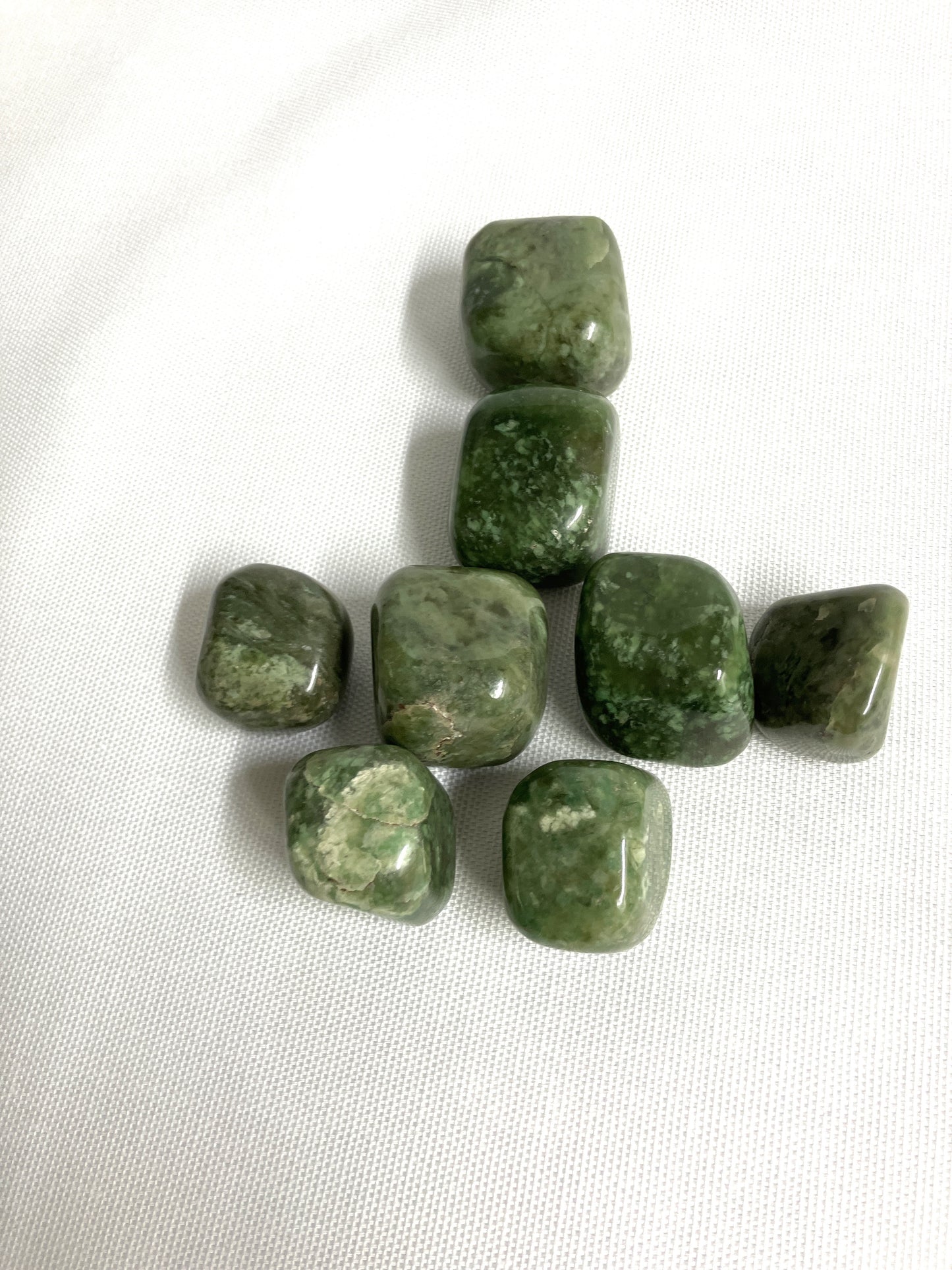 Front view of Grossularite Crystal aka Green Garnet on a white fabric background