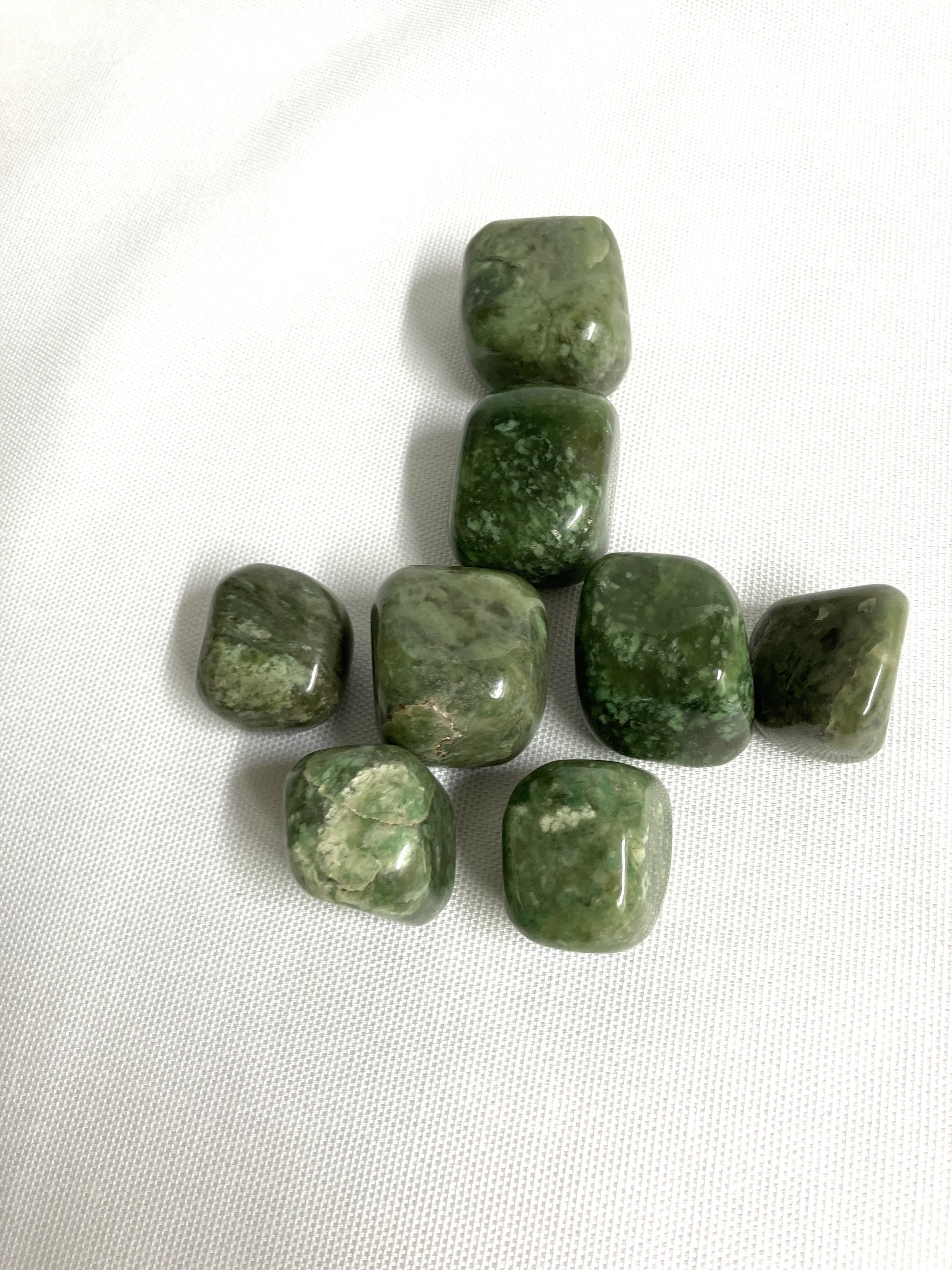 Front view of Grossularite Crystal aka Green Garnet on a white fabric background