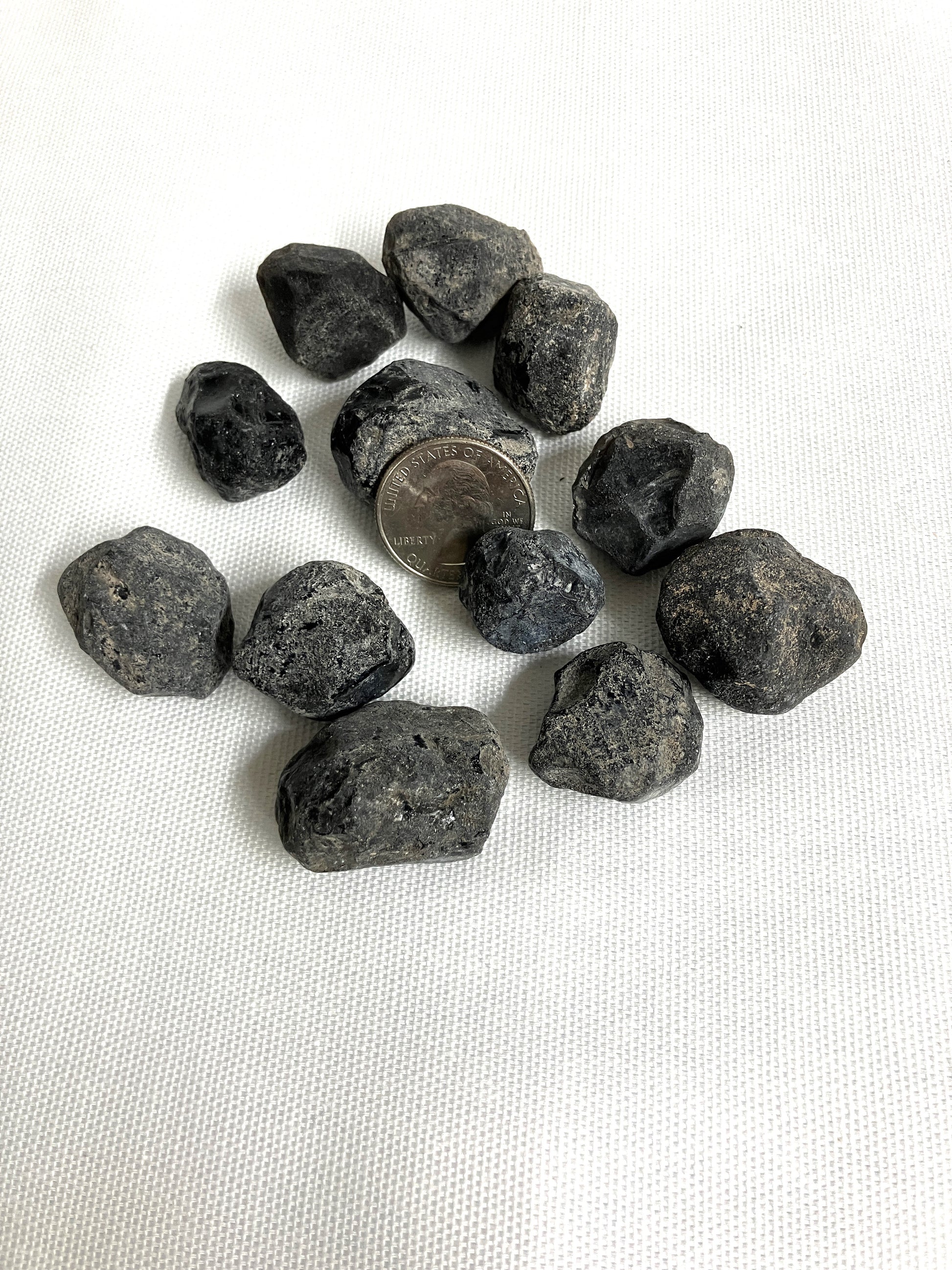 Rough Apache Tears with a quarter for scale on a white fabric background