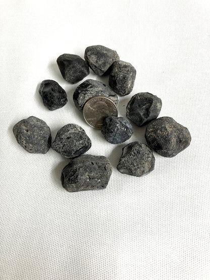 Rough Apache Tears with a quarter for scale on a white fabric background