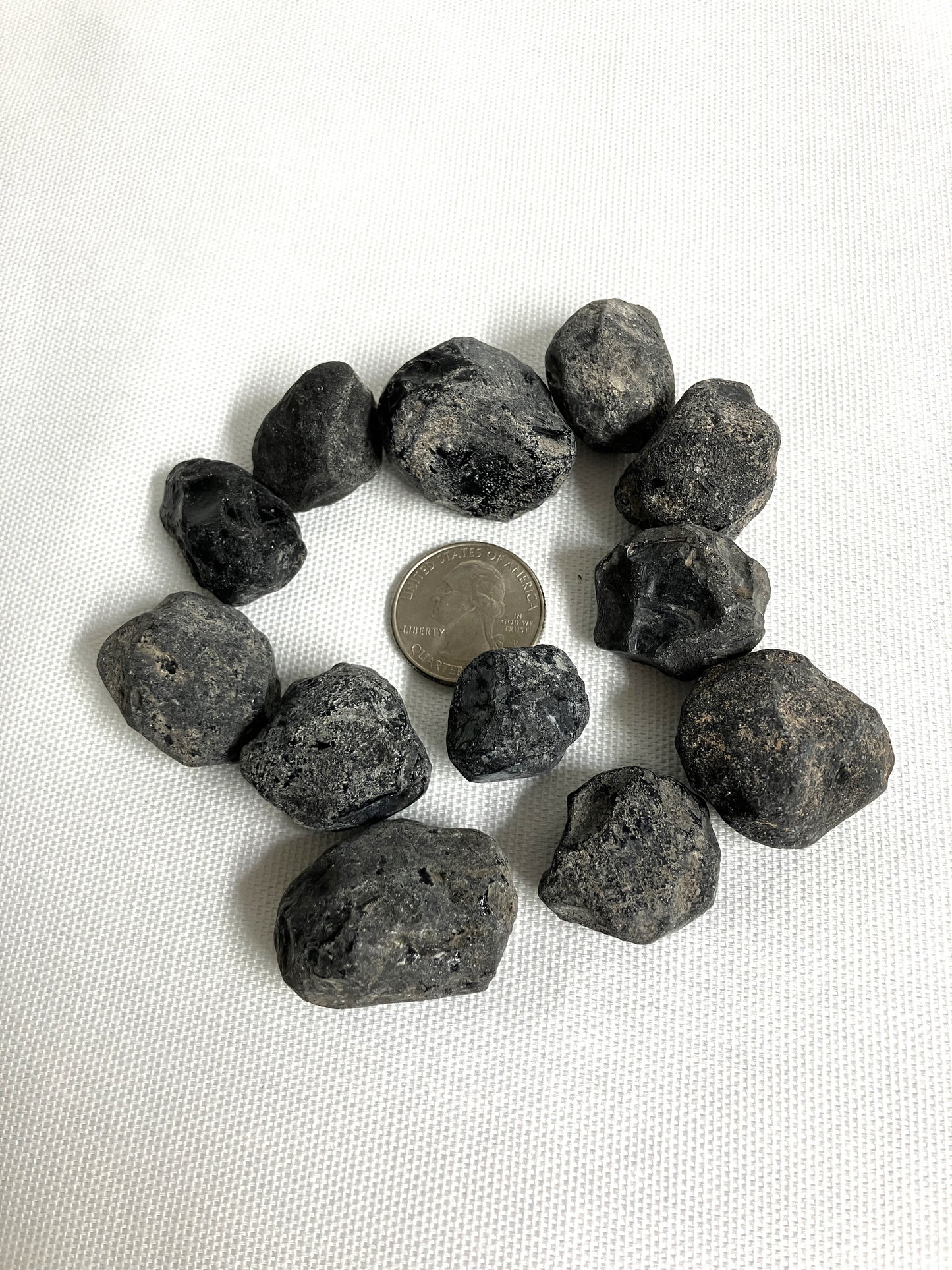 Rough Apache Tears stones on a white fabric background