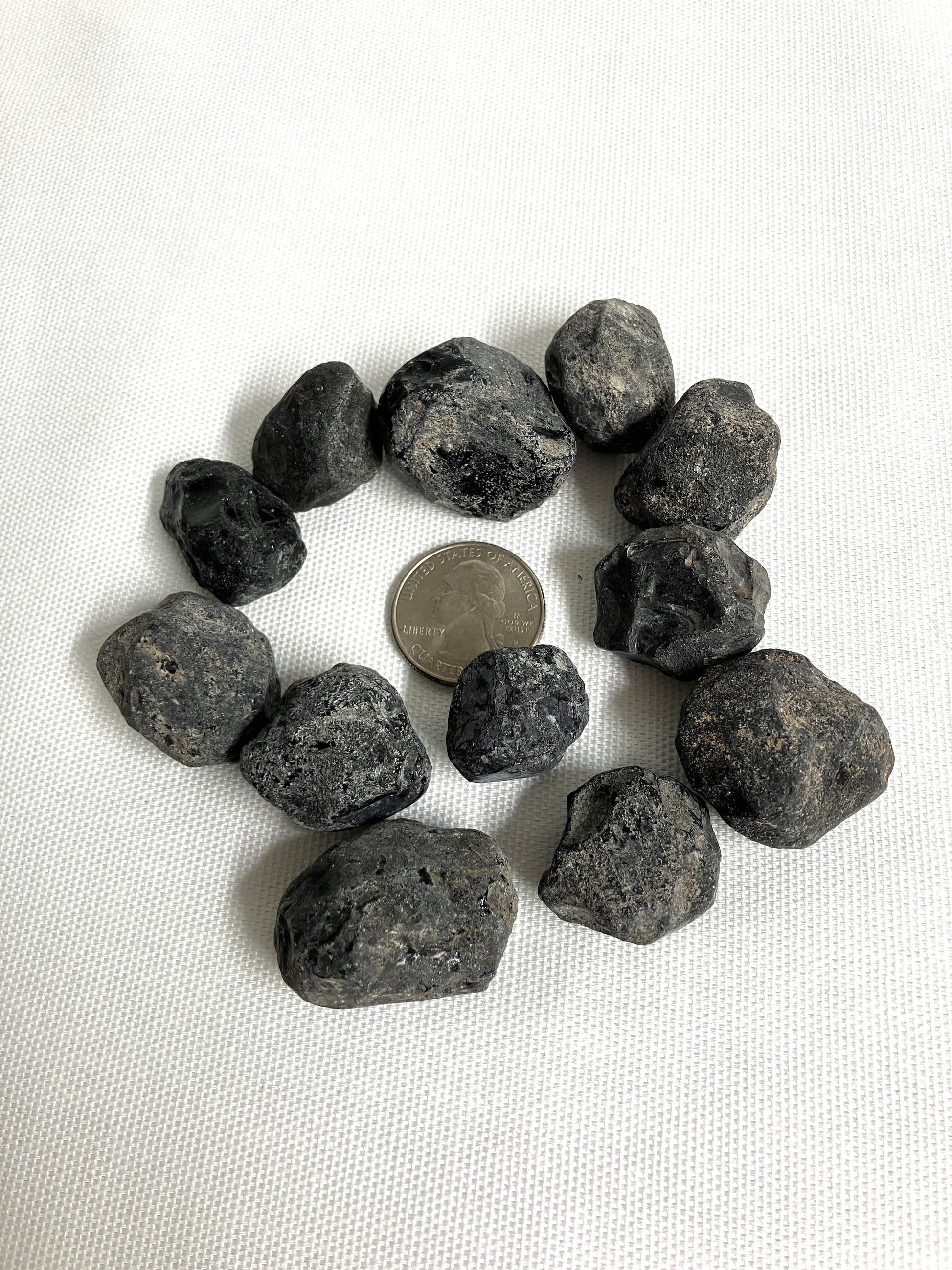 Rough Apache Tears stones on a white fabric background