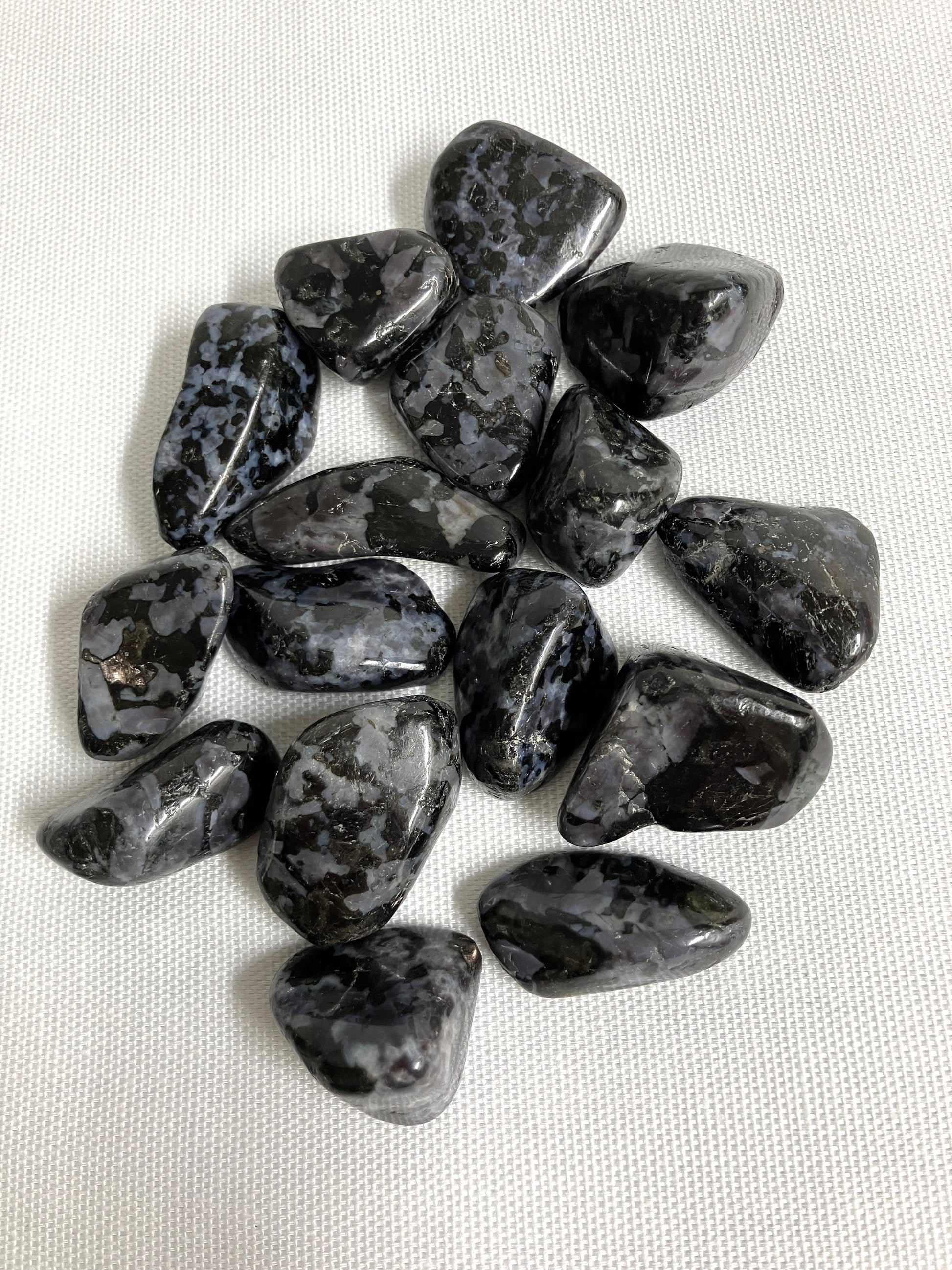 Bottom view of Indigo Gabbro Tumbled Crystals on a white fabric background