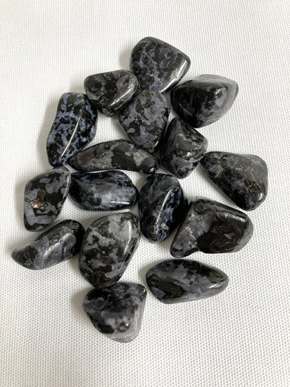 Bottom view of Indigo Gabbro Tumbled Crystals on a white fabric background