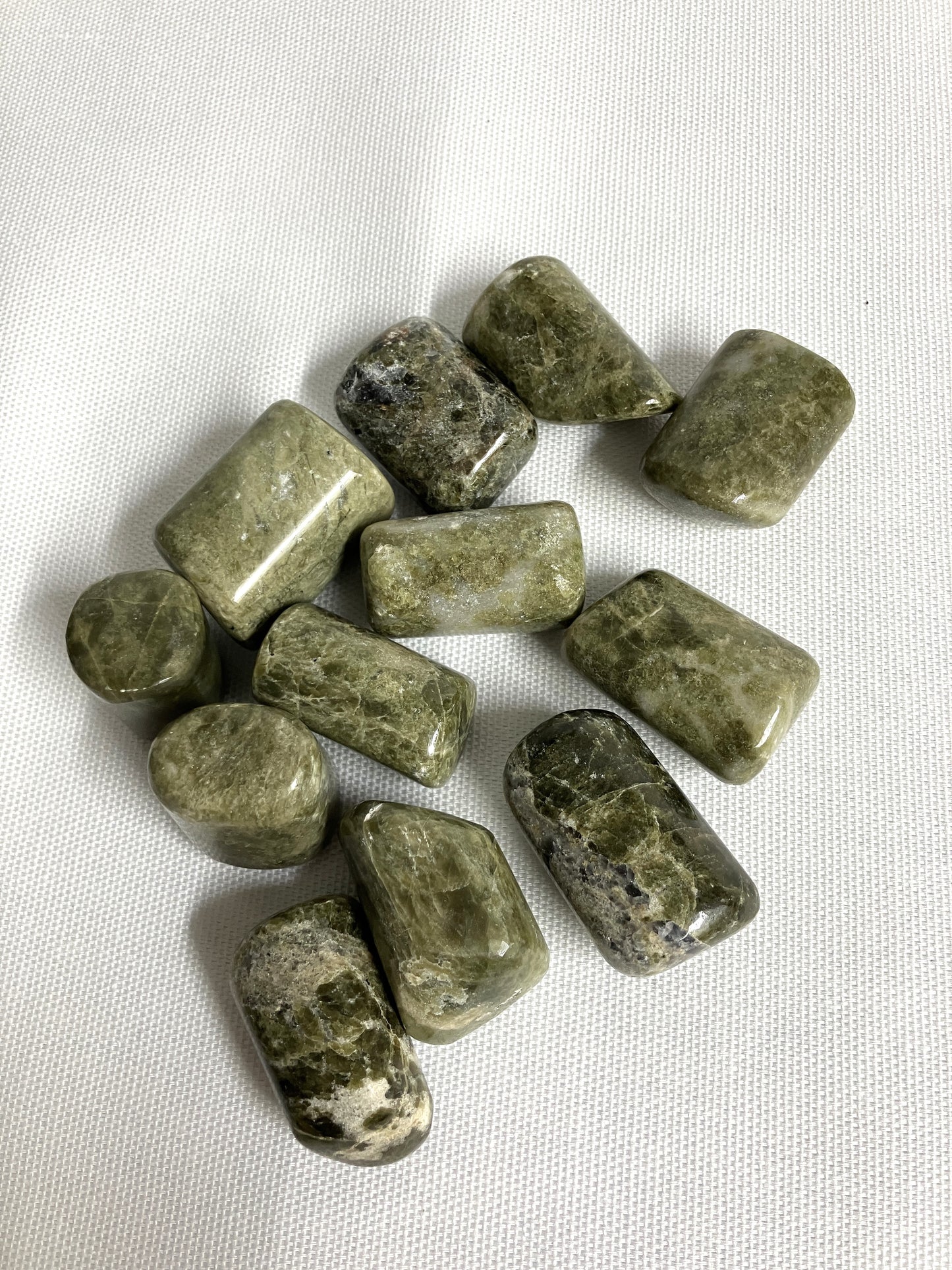 Front view of Vesuvianite Tumbled Crystals on a white fabric background