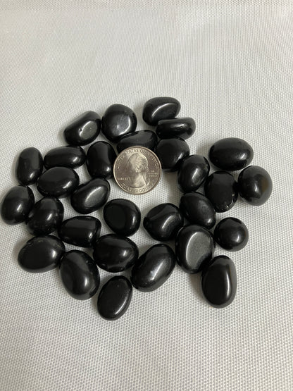 Shungite Crystals  on a light gray background with a quarter for scale