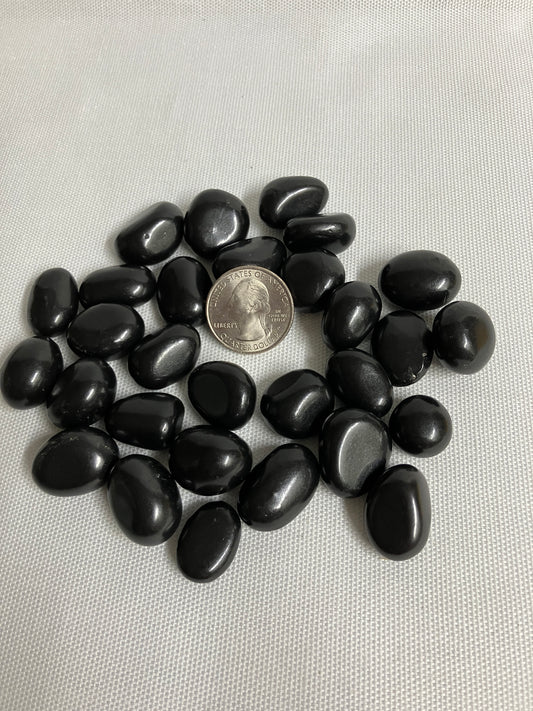 Shungite Crystals  on a light gray background with a quarter for scale