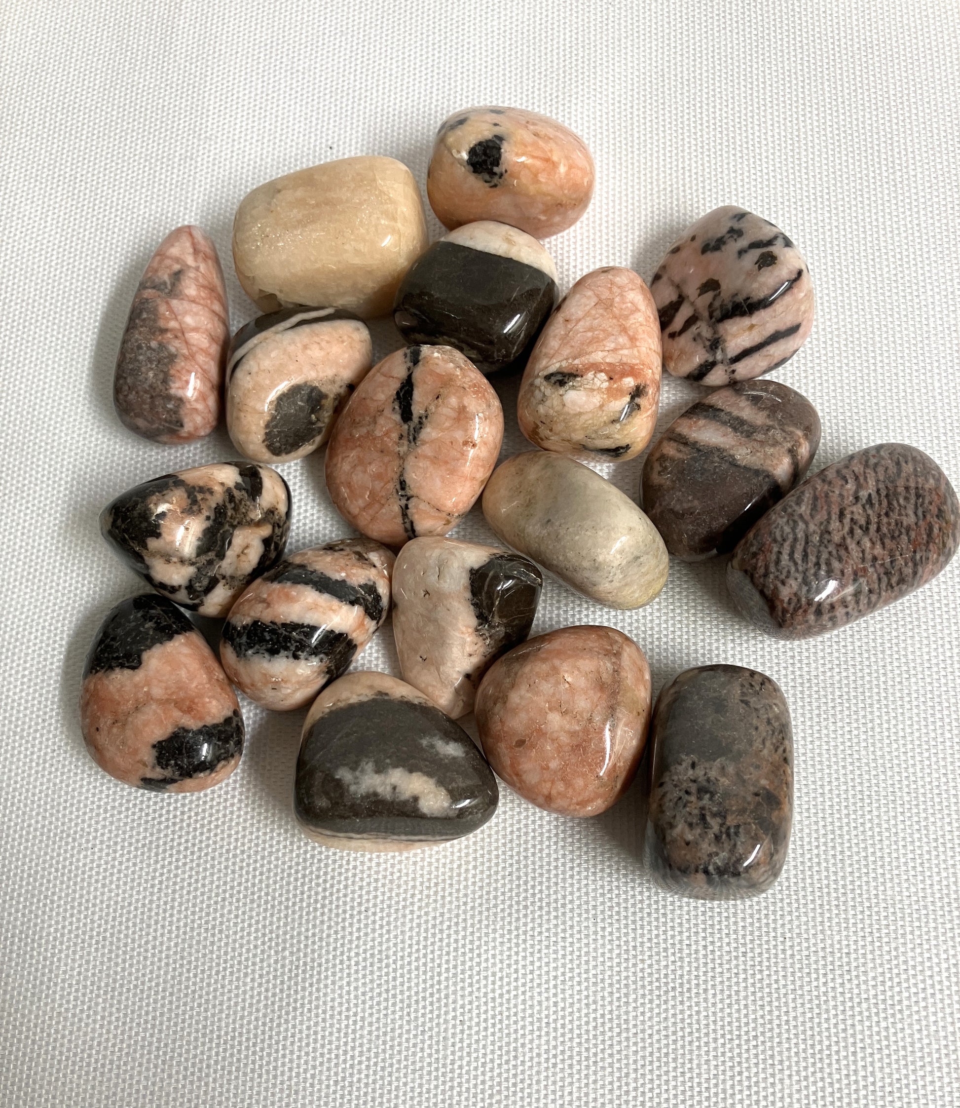 Back view of Pink Zebra Jasper Crystals showing patterns and color variants on a textured white surface