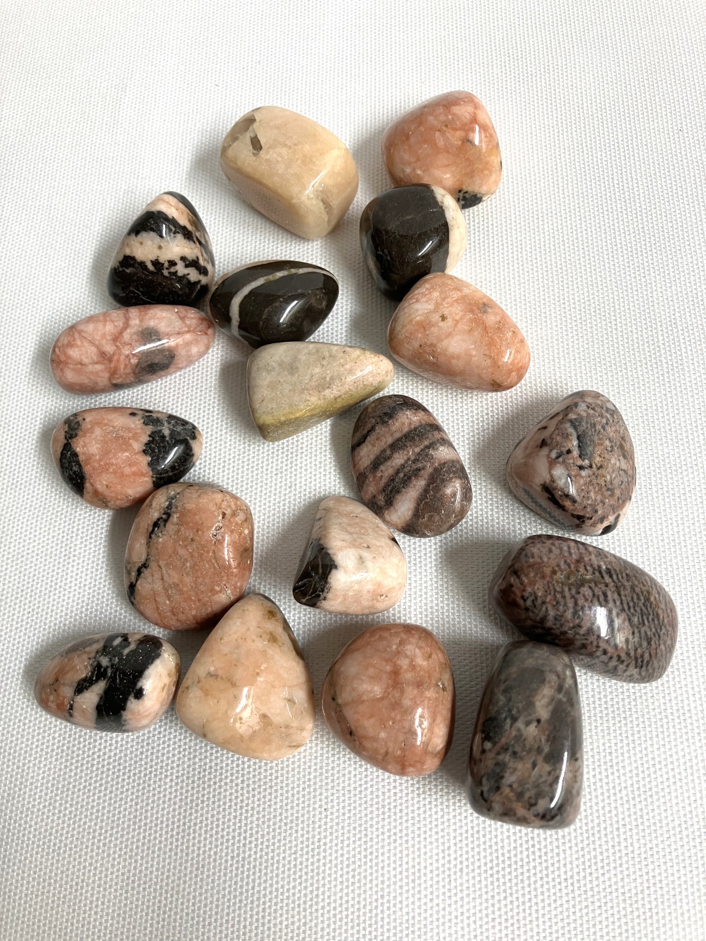 Assorted Pink Zebra Jasper Crystals on a white fabric background
