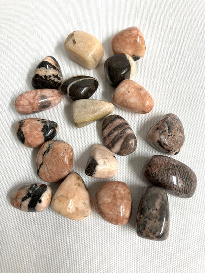 Assorted Pink Zebra Jasper Crystals on a white fabric background