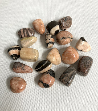 Group of Pink Zebra Jasper Crystals, variously shaped and colored placed on a light fabric background