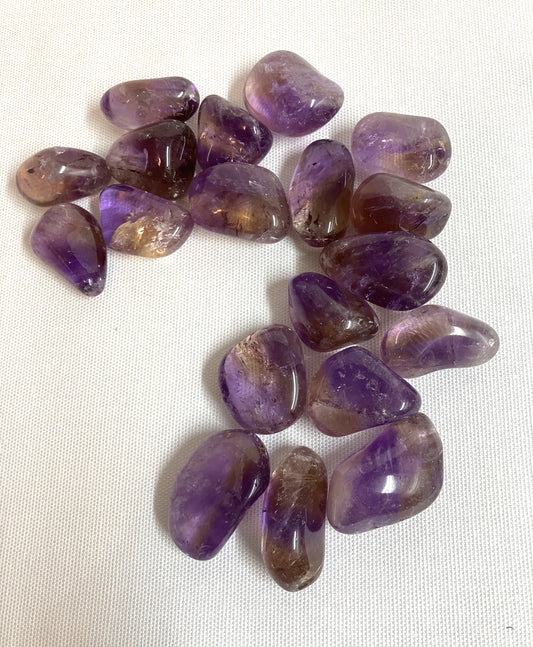 View of Ametrine Tumbled  Crystals on a white fabric background