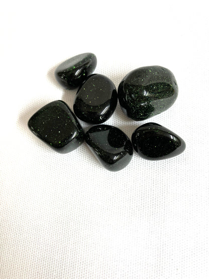 Tumbled Green Goldstone Crystals showing a alternat view on a white fabric background