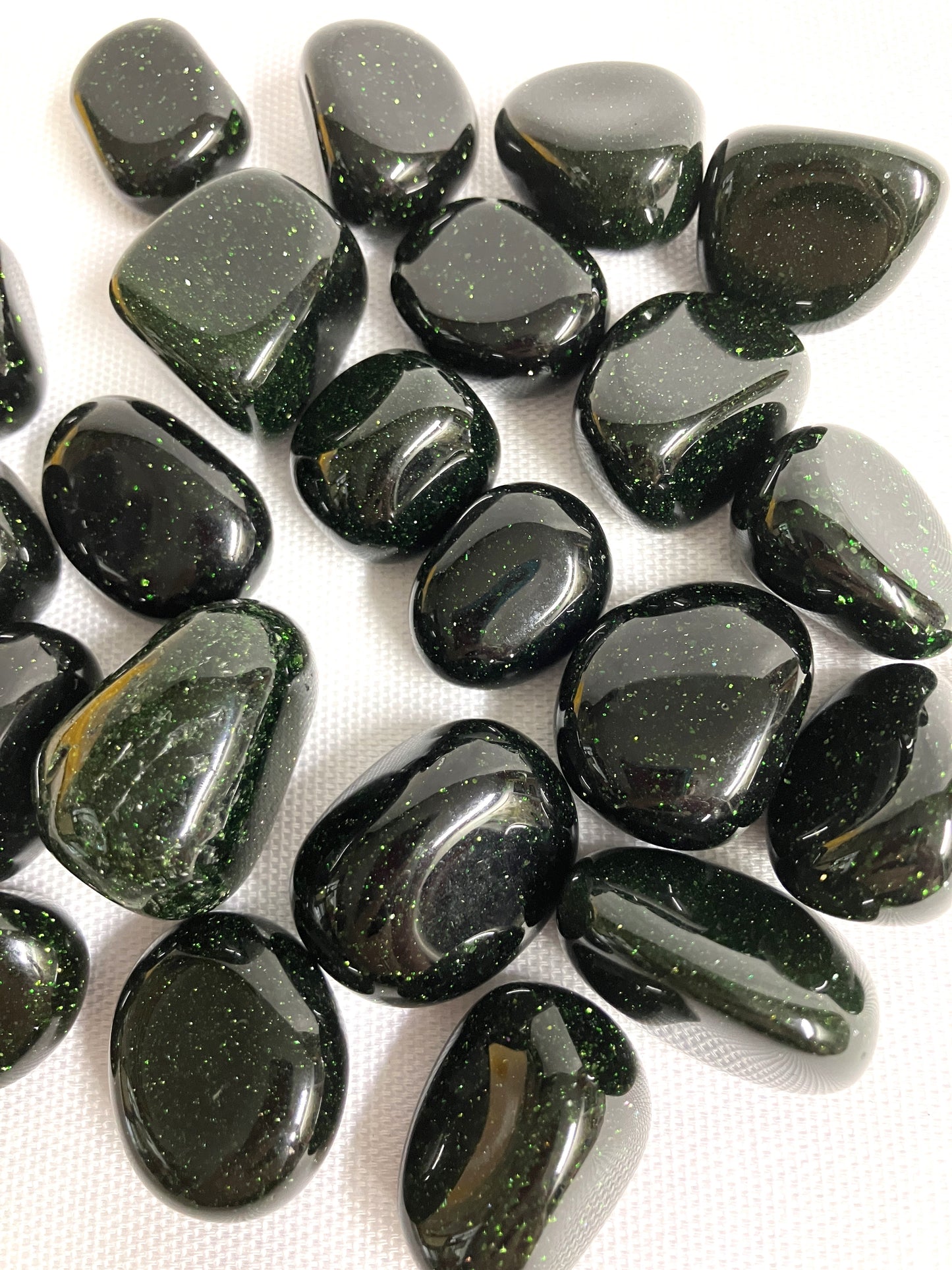 Group of Tumbled Green Goldstone Crystals showing different views on a white background