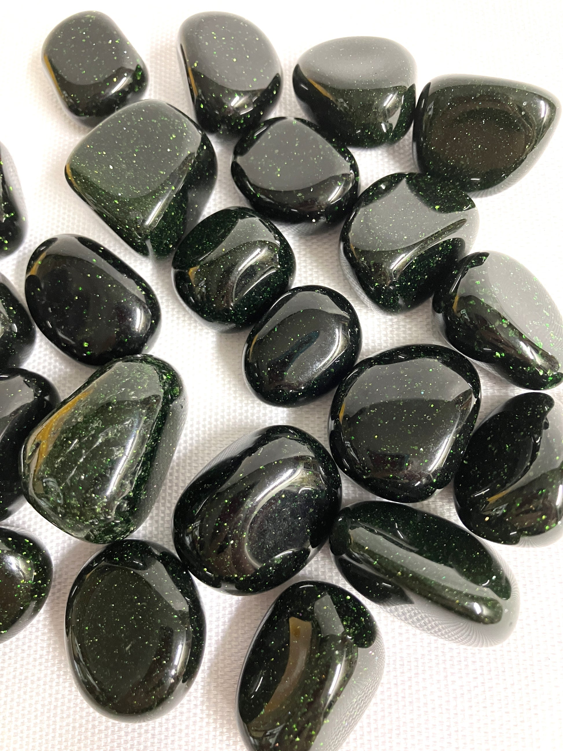 Group of Tumbled Green Goldstone Crystals showing different views on a white background