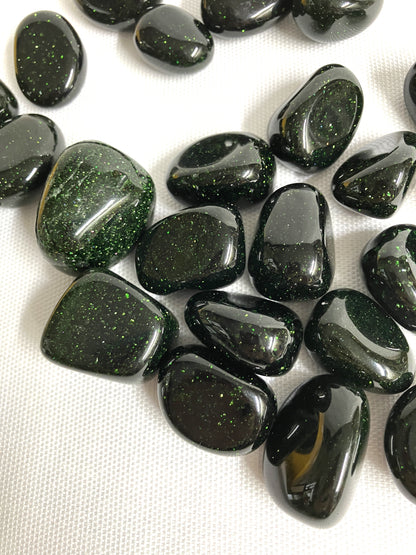 Collection of Tumbled Green Goldstone Crystals on a white fabric background