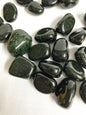 Collection of Tumbled Green Goldstone Crystals on a white fabric background