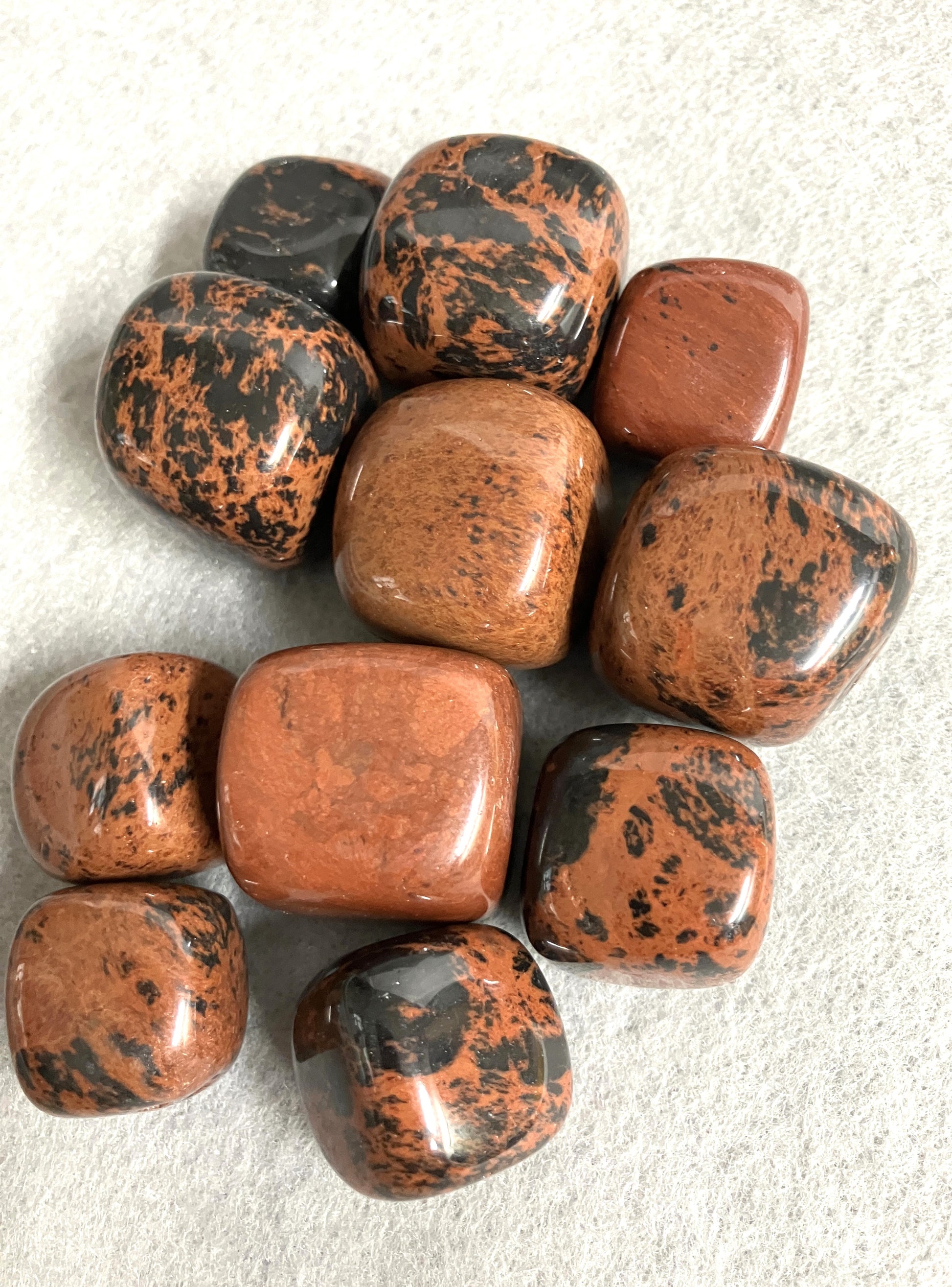 Collection of Mahogany Obsidian Crystals showing the variations in coloring and pattern on a light gray background