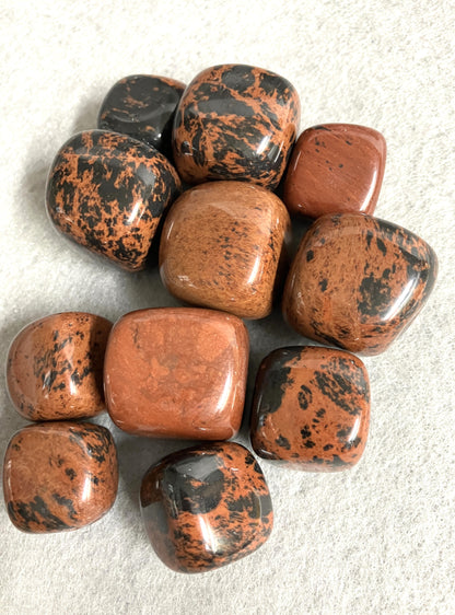 Collection of Mahogany Obsidian Crystals showing the variations in coloring and pattern on a light gray background