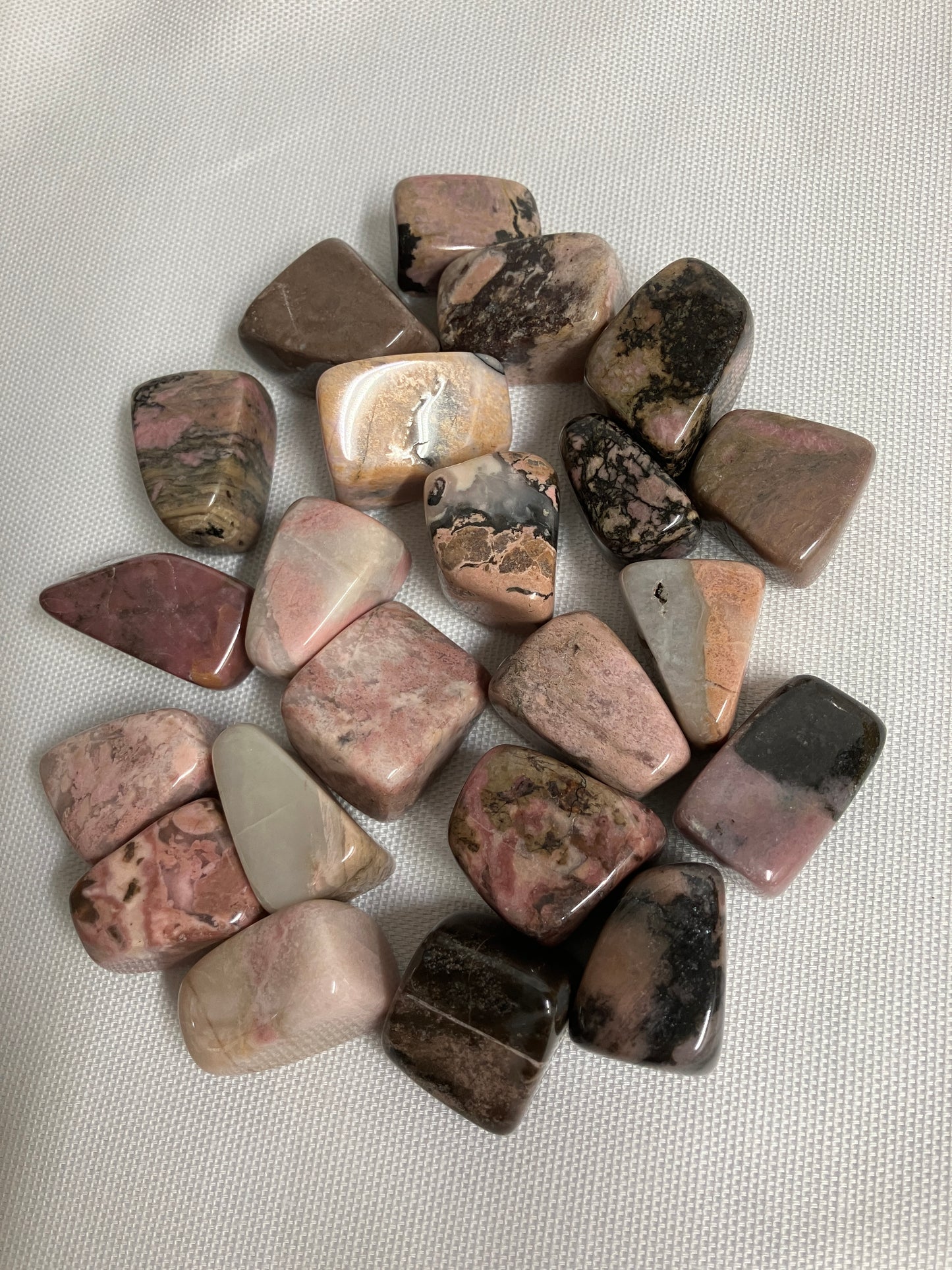 Collection of polished Rhodonite Crystals on a light gray background