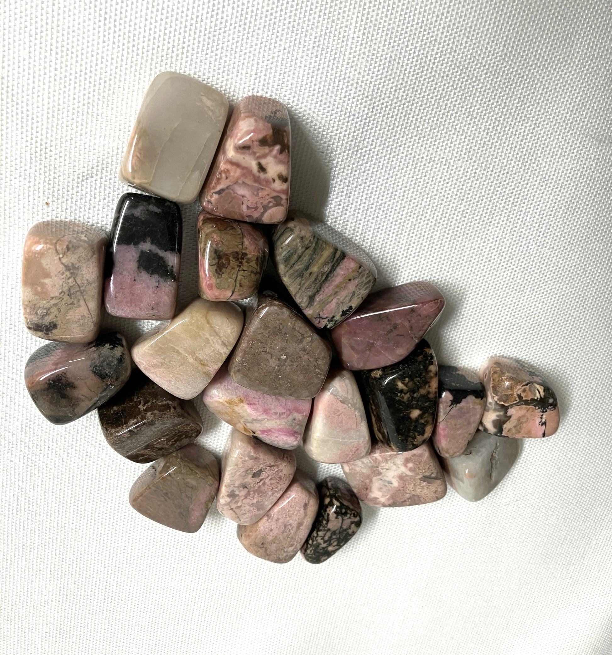 Group of Tumbled Rhodonite Crystals on a white fabric background