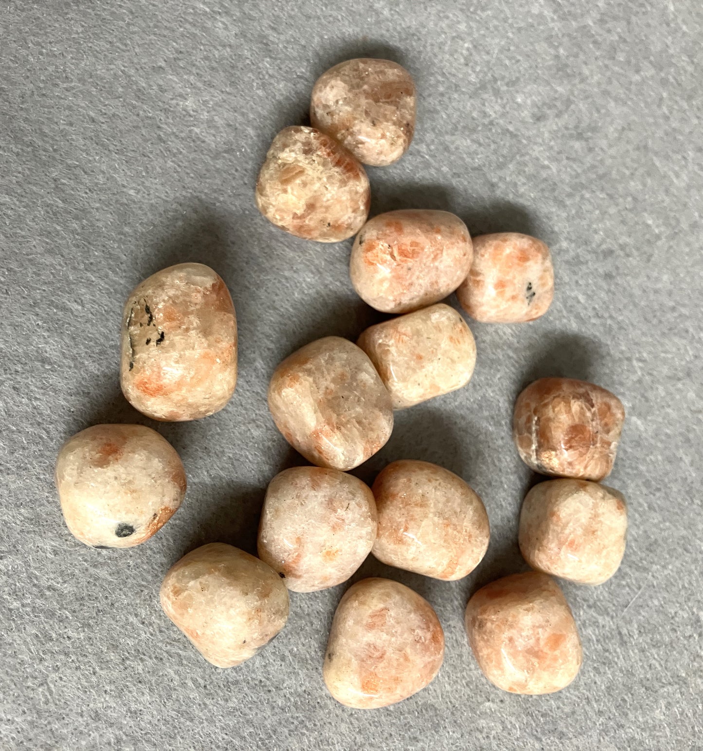 Group of Sun Stone Crystals showing different patterns and shades of color on a gray surface