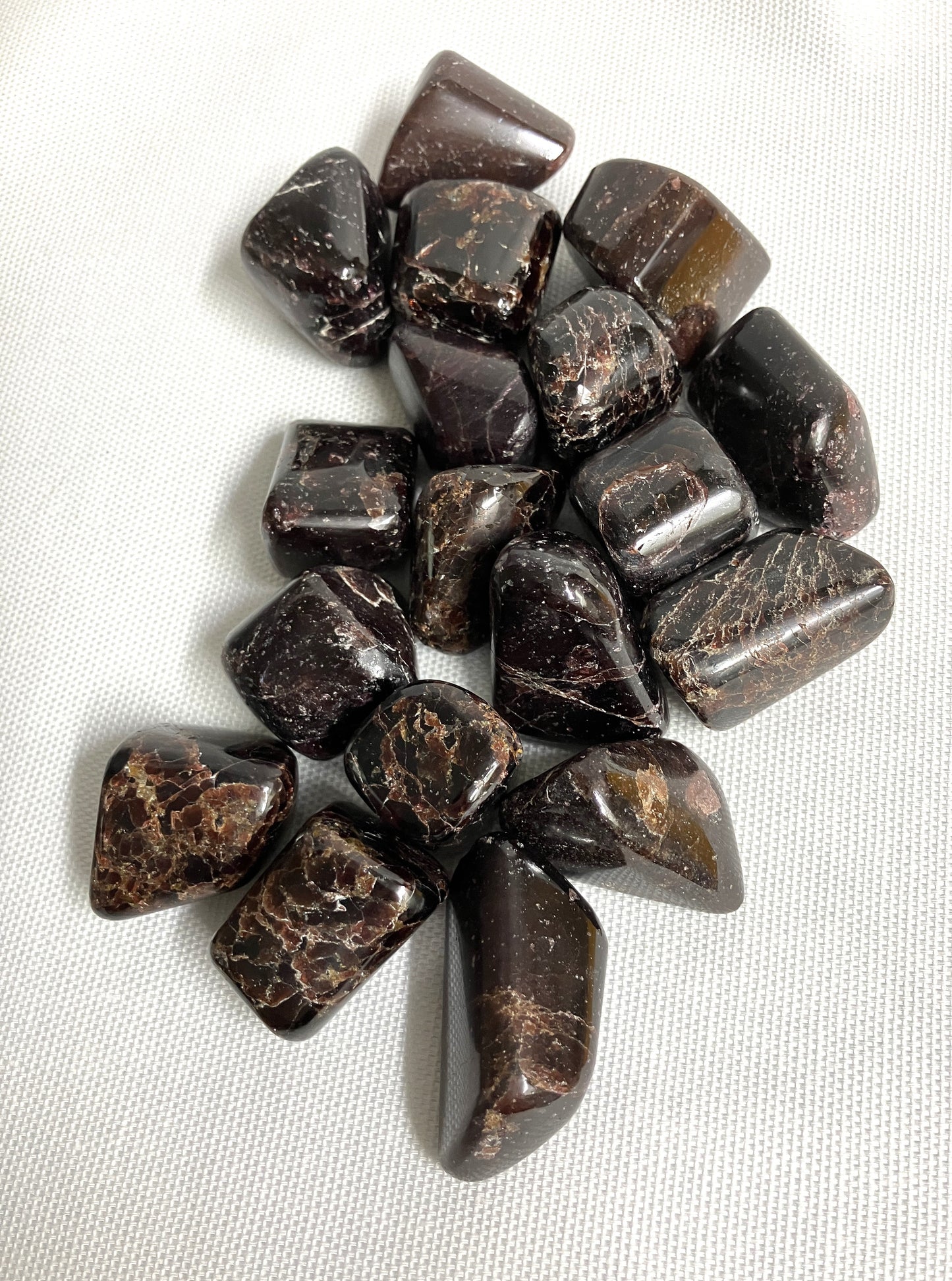 Group of Almandine Garnet Crystalstumbled stones on a white fabric background