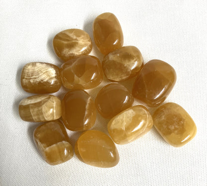 Tumbled Honey Caramel Calcite Crystals on a white fabric background