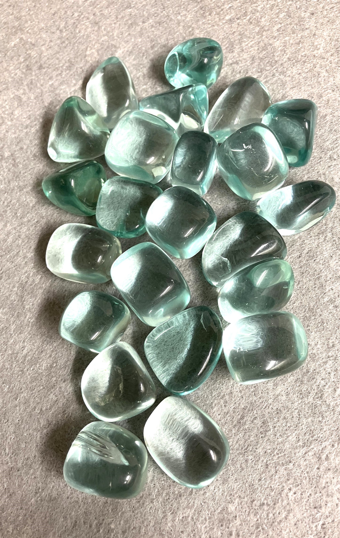Blue Obsidian Crystals displayed in a large group on a beige surface