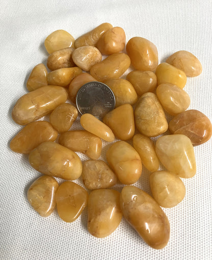 Grouping of Apricot Quartz Crystals on a white background with a quarter coin for scale.