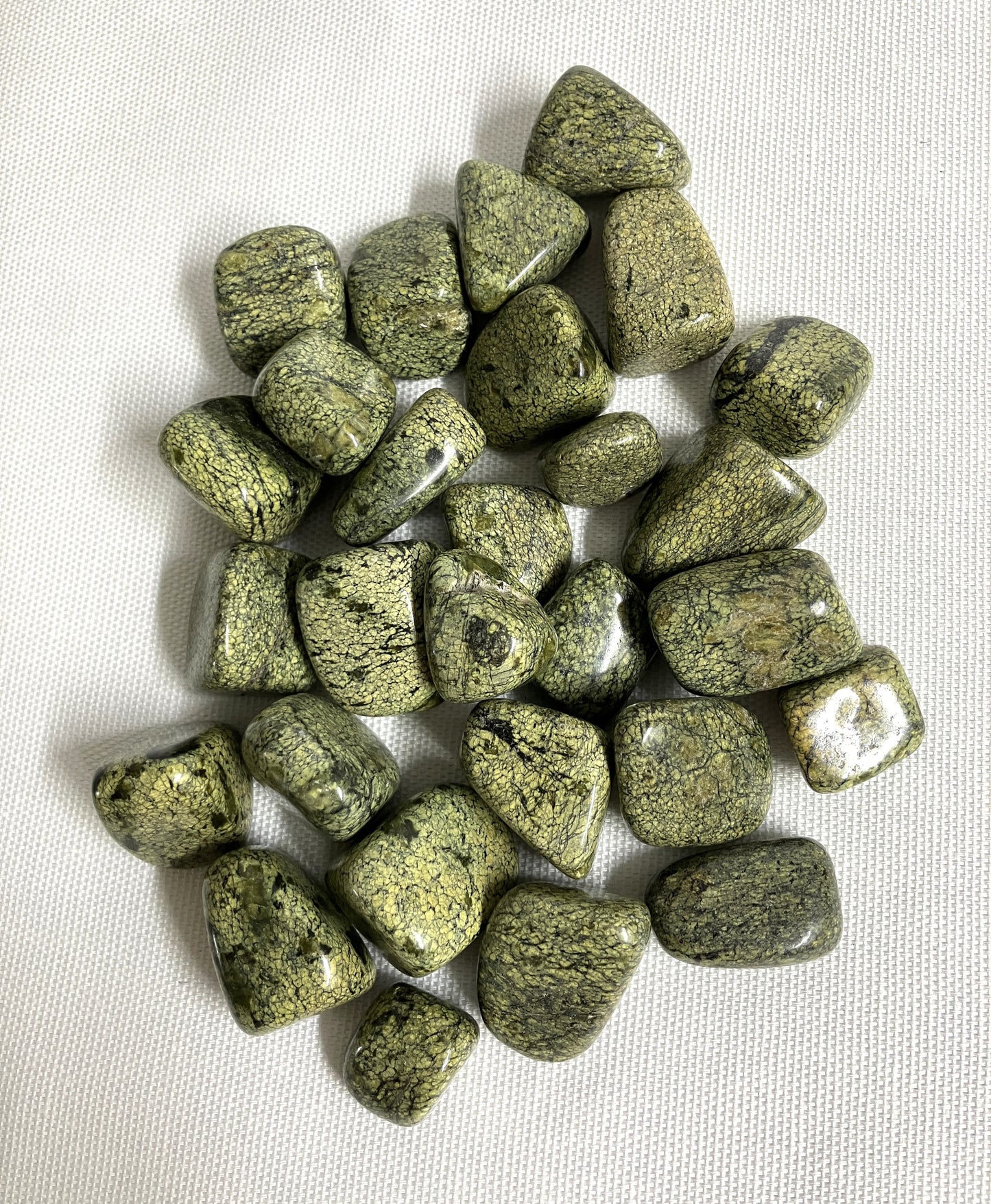 Front view of Asterite Serpentine Crystals on a white fabric background