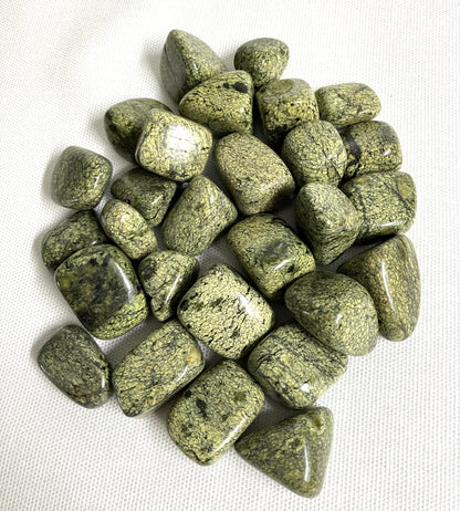 Tumbled Asterite Serpentine Crystals on a white fabric background