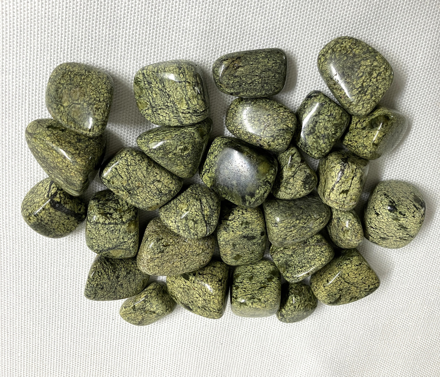 Collection of Asterite Serpentine Crystals on a white fabric background