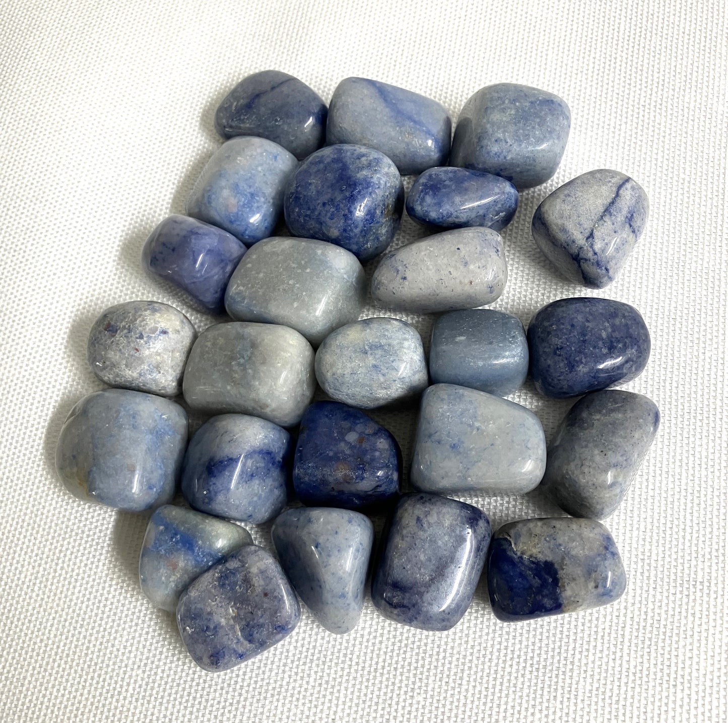 Closeup of Tumbled Dumortierite Crystals on a white fabric background