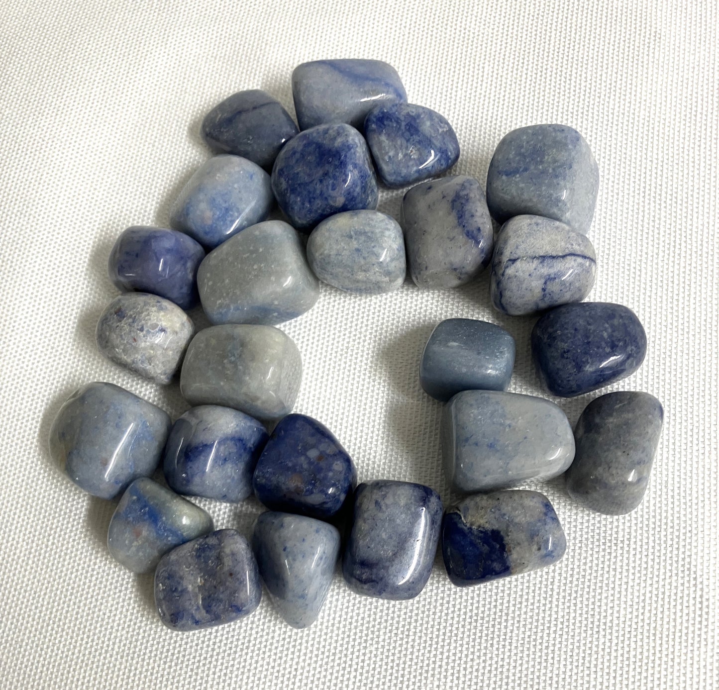 Tumbled Dumortierite Crystals shown on a white fabric background