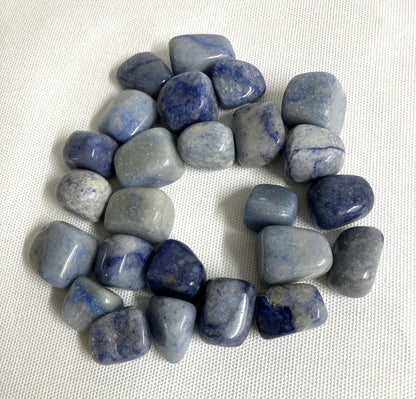 Tumbled Dumortierite Crystals shown on a white fabric background