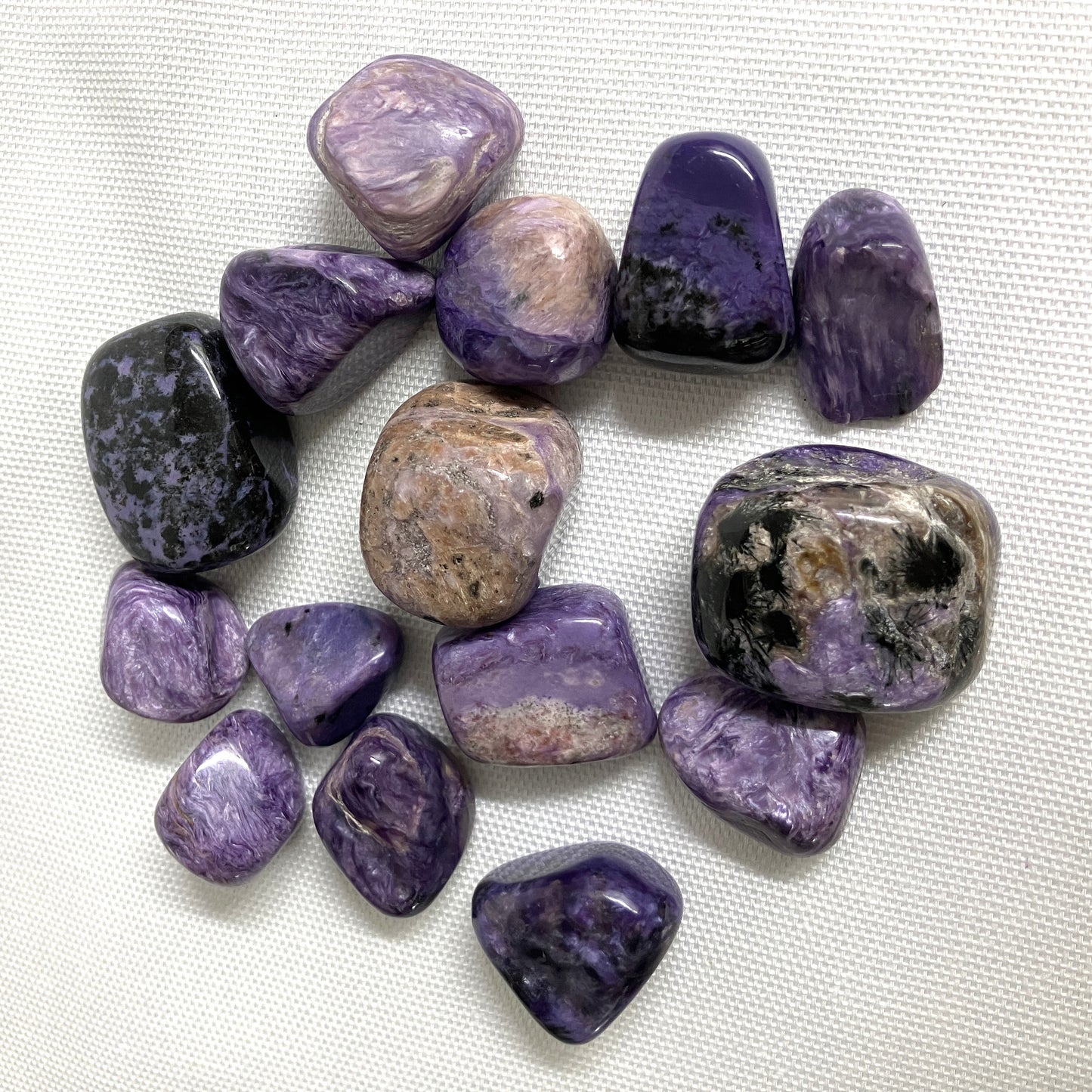 Closeup of Charoite Tumbled Crystals on a white background