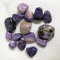 Closeup of Charoite Tumbled Crystals on a white background