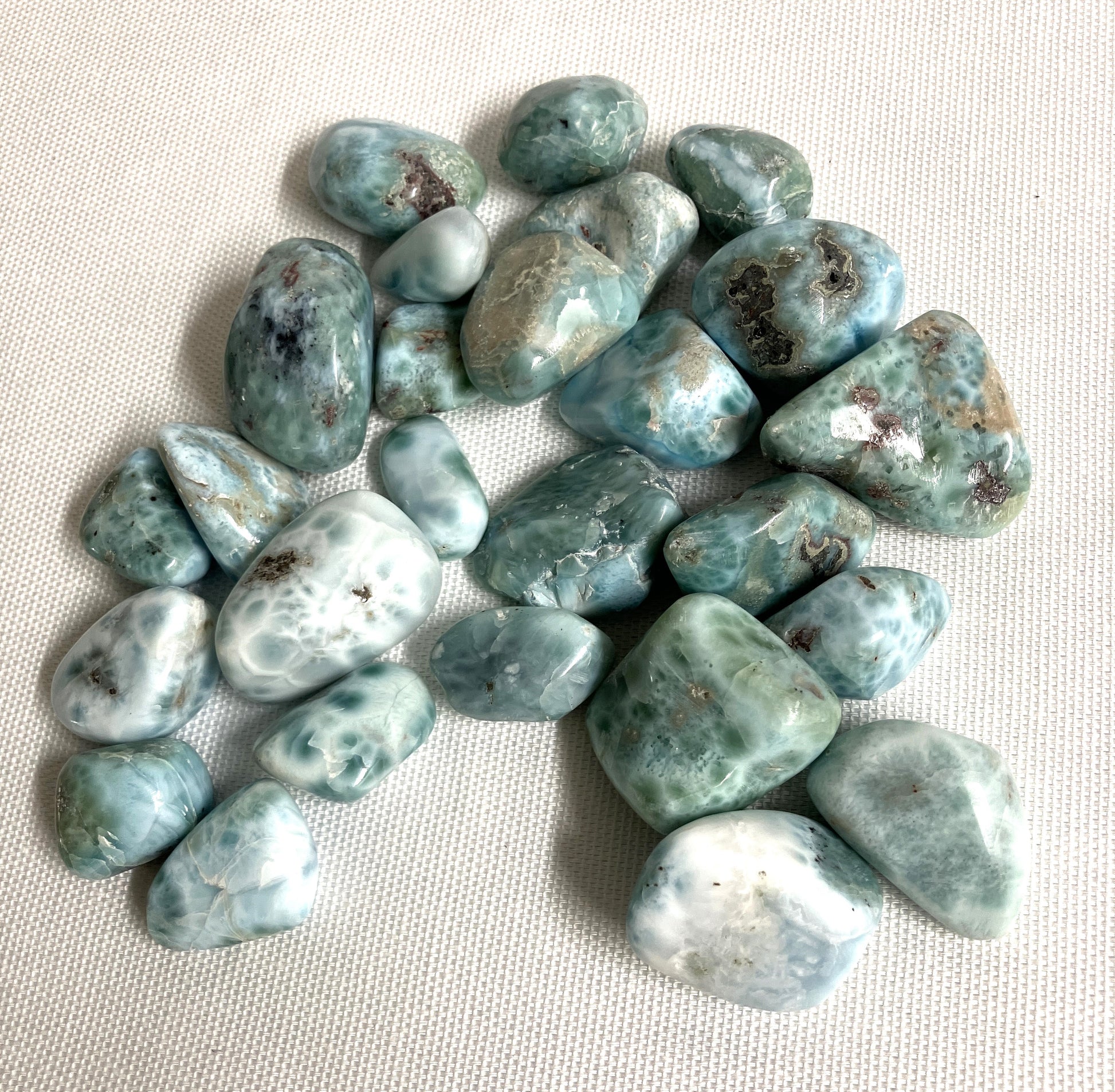 Tumbled Larimar Crystals on a textured beige surface