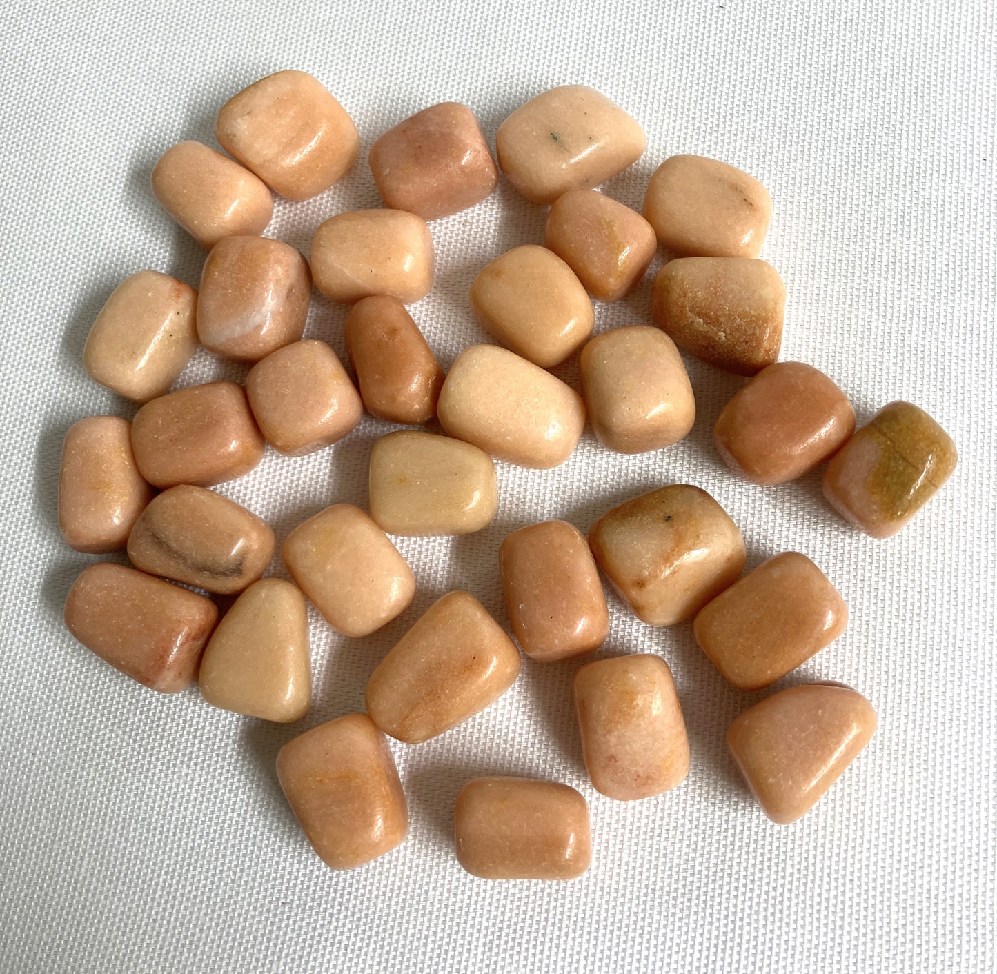 Tumbled Peach Calcite Crystals on a white fabric background