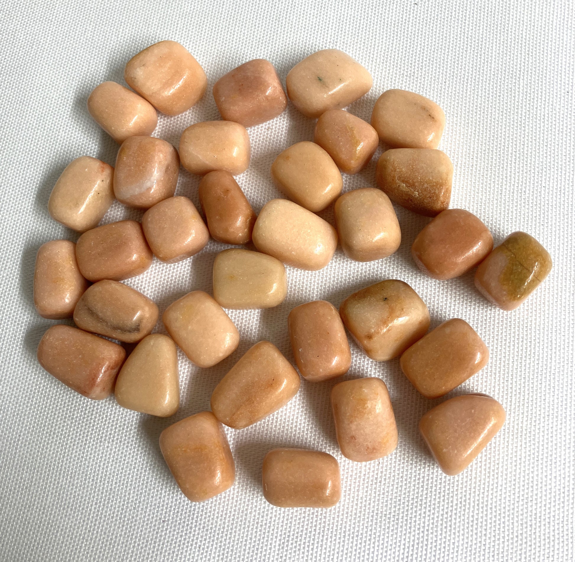 Tumbled Peach Calcite Crystals on a white fabric background