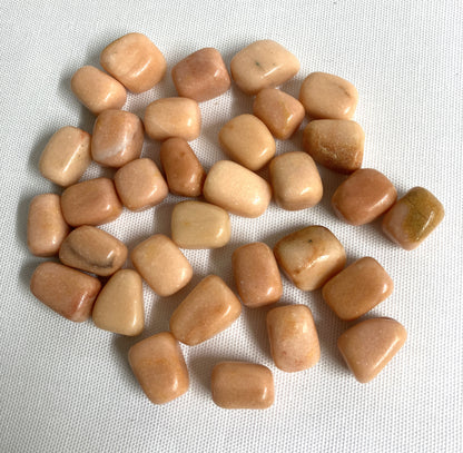 Tumbled Peach Calcite Crystals on a white fabric background