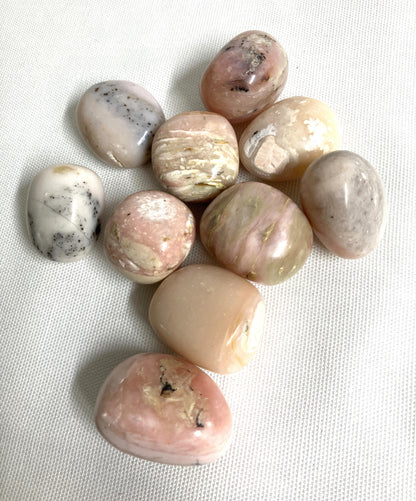 Collection of Pink Opal Crystals showing difference colors and patterns on a textured white surface