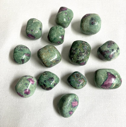 Assorted Ruby Fuchsite Crystals showing the variation of patterns and colors on a white fabric background