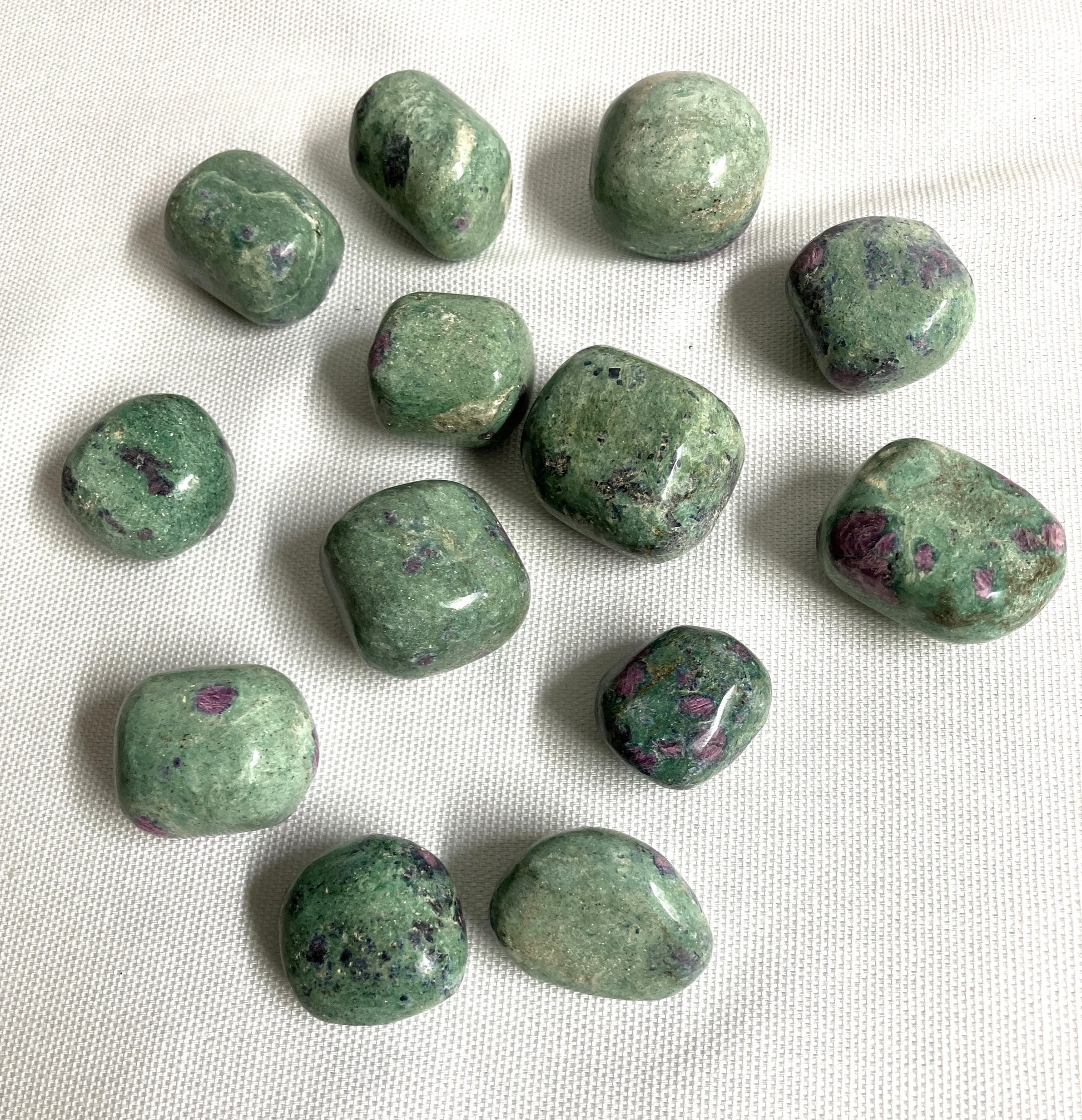 grouping of Ruby Fuchsite Crystals on a white fabric background
