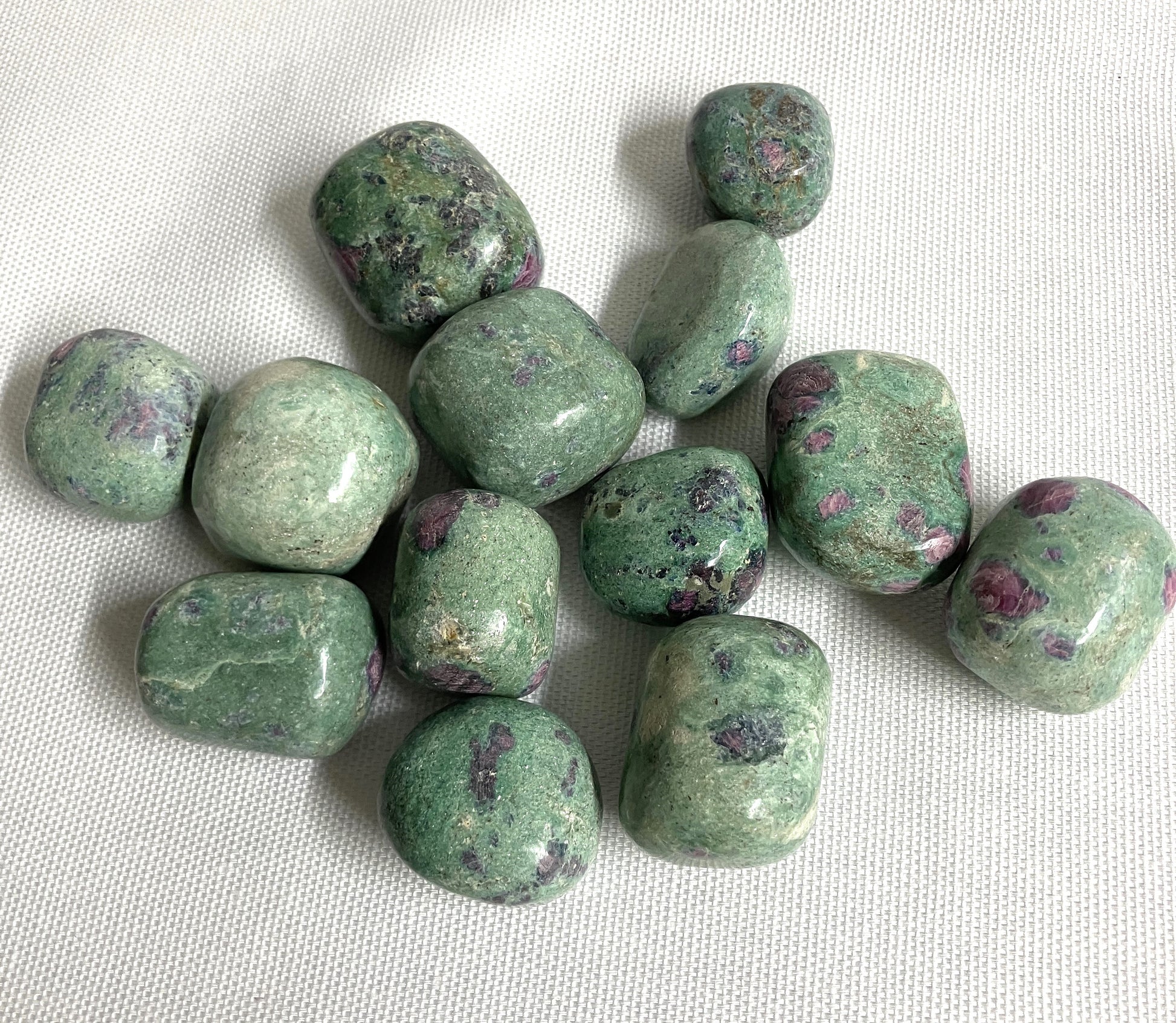 Assorted Ruby Fuchsite Crystals on a white fabric background
