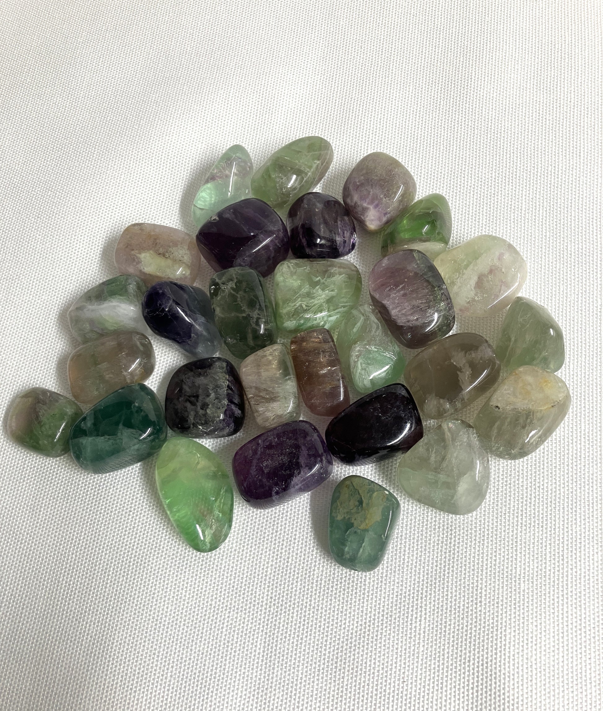 Assorted Fluorite Crystals showing color and size on a white fabric background